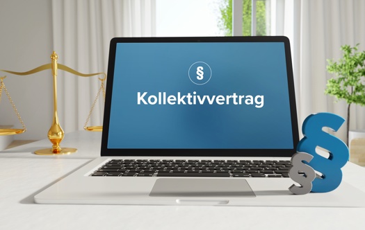 Laptop im Büro mit Begriff Kollektivvertrag auf dem Monitor - daneben Paragraf und Waage